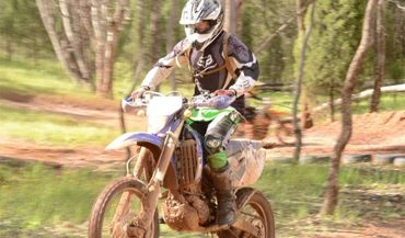 A man riding an offroad motorcycle over a dirt jump